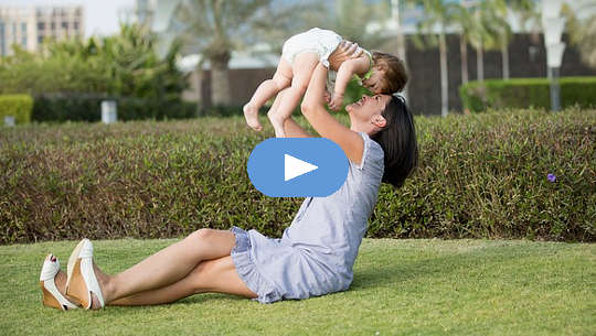 Loving Relationships and a Peaceful Soul smiling mother, sitting on the grass, holding up a child