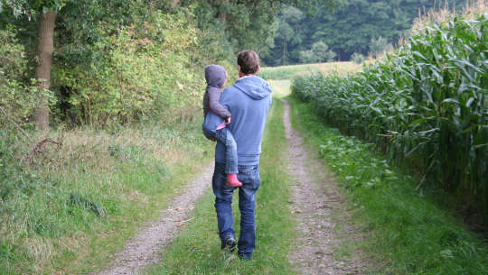 Seeking Freedom From or Freedom To? father holding son in his arms and walking down the road