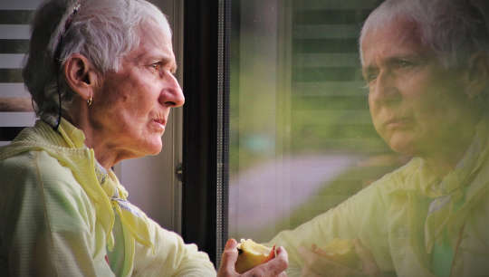What Getting Old Really Feels Like For Some older person eating an apple and looking at her reflection in a window