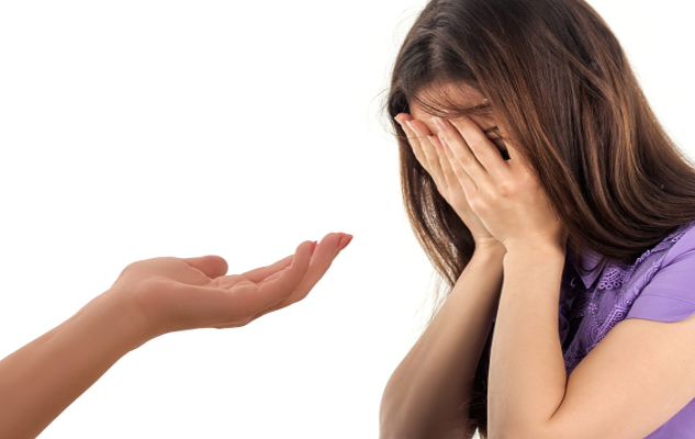How to Empathize Without Taking on People’s Stress a hand held open to a young woman with her face covered by her hands