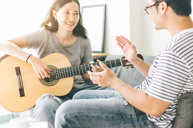 How to Write a Love Song a woman playing guitar sitting in front of her partner