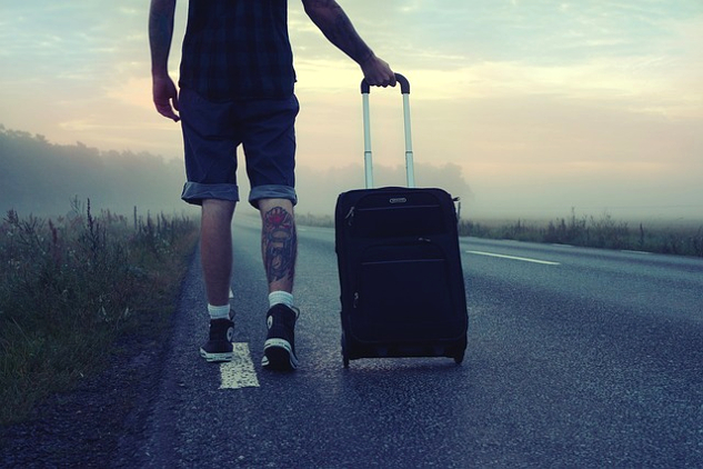 How Do You Pack for One Year on the Road (with Kids)? a traveler pullilng a carry-on bag with wheels