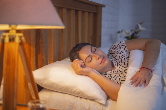 The Power of Sound to Help You Sleep Better Every Night woman sleeping with a slight smile on her face