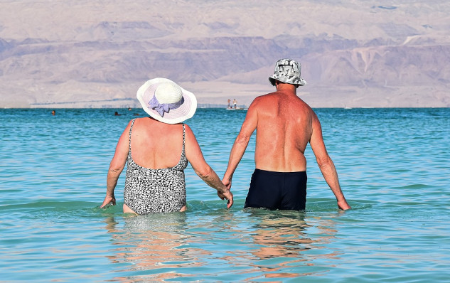 Healing Feminine and Masculine Energy: A Path to Balance an older woman and man holding hands and walking into the calm waters of the ocean