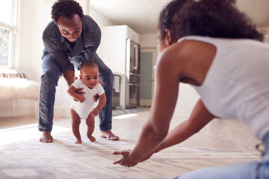 Parents playing with their new child on a bed
